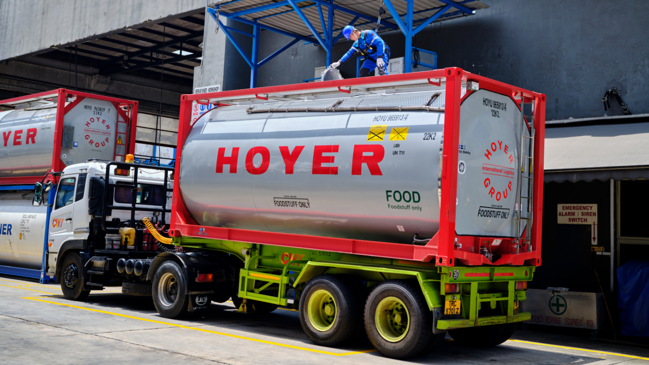 HOYER food tank container on truck with worker in protective gear inspecting top of tank