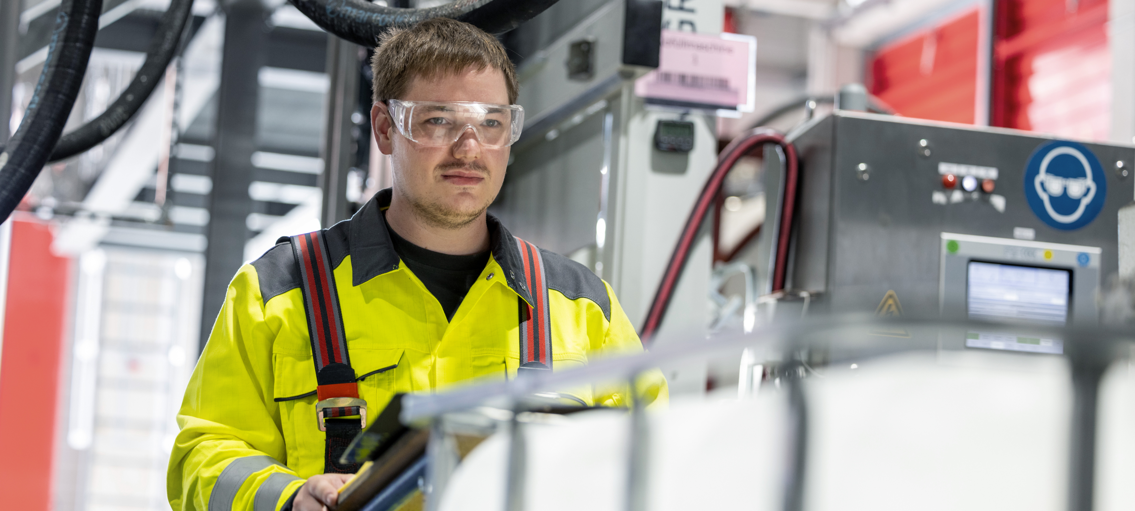 Employee in high-visibility jacket performing IBC filling in an industrial environment as part of HOYER SCS services